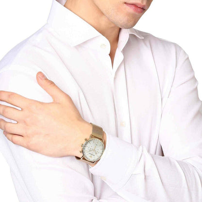 Gold chronograph watch with cream dial worn on wrist over white shirt