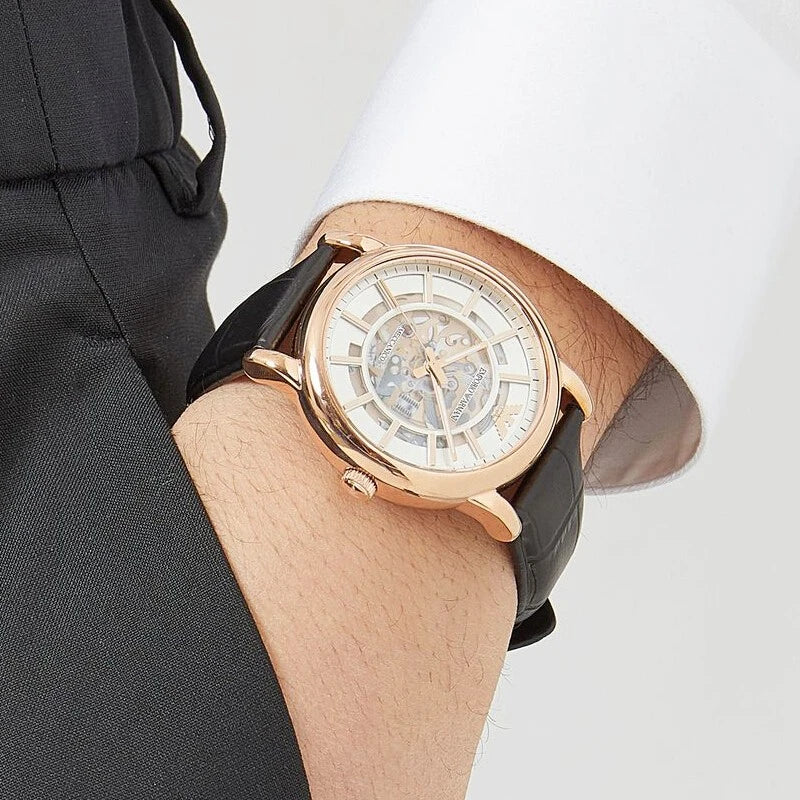 Rose gold skeleton dial watch worn on wrist with black leather strap
