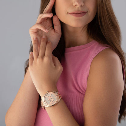 Michael Kors Janelle rose gold-tone watch worn on wrist by woman
