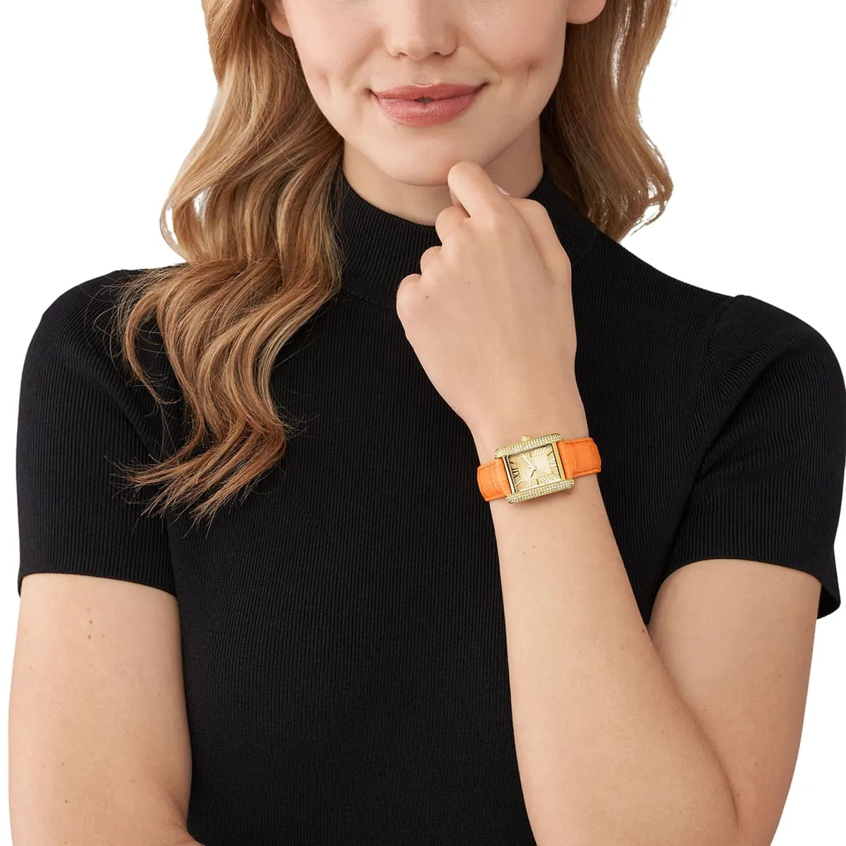 Michael Kors Emery watch worn on wrist, showing gold-tone case and orange leather strap