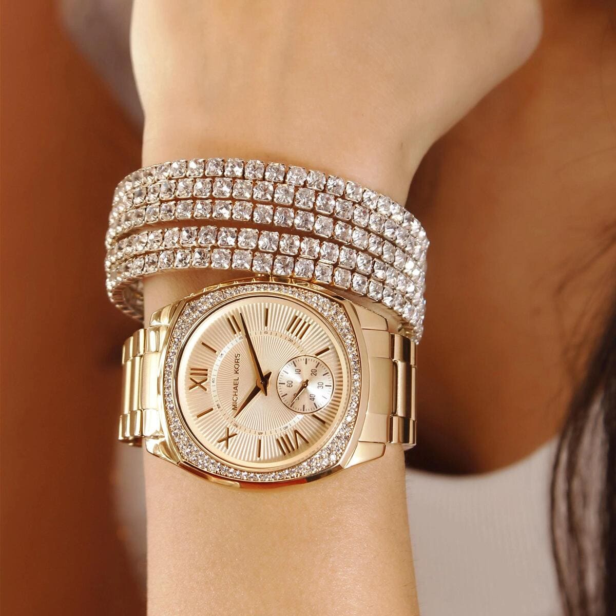 Michael Kors Bryn gold watch worn on wrist with gold metal bracelet